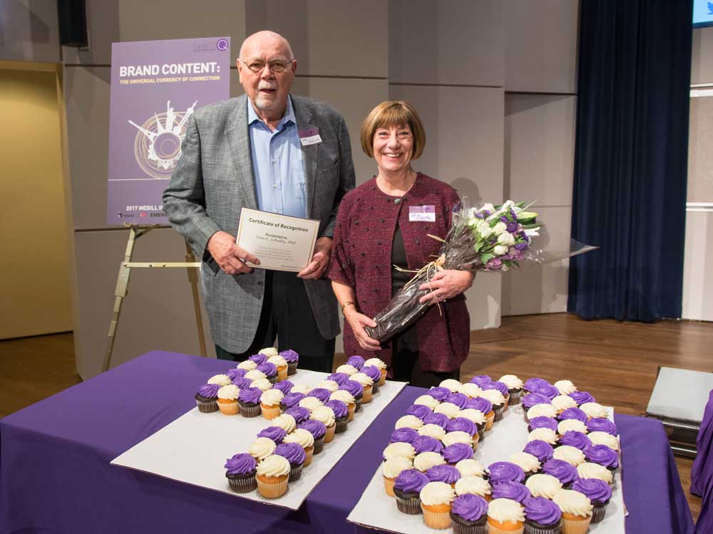 Don Schultz poses for a photo with his wife, Heidi Schultz, in front of a table that has cupcakes in the shape of "40"