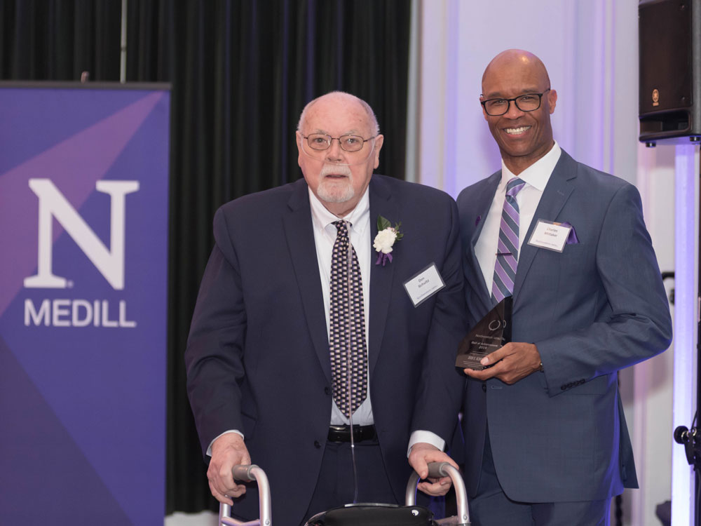 Don Schultz stands with Medill Dean Charles Whitaker, who holds a crystal award, at Medill's Hall of Achievement reception