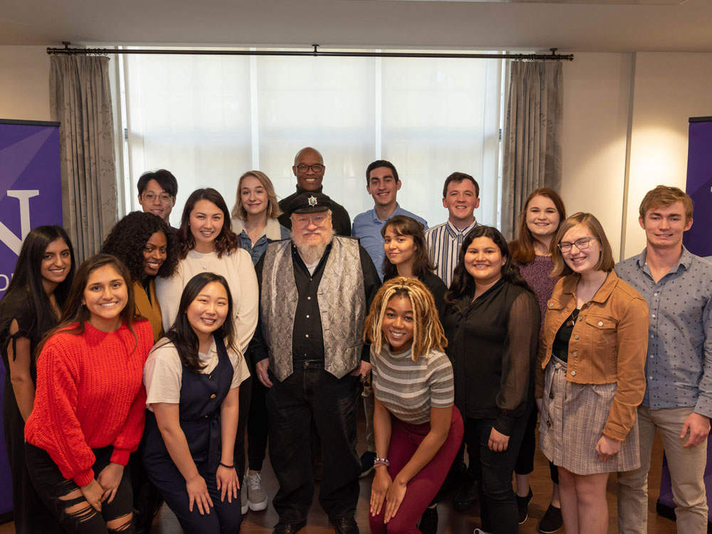 Medill alumnus George RR Martin poses for a photo with Medill students and Dean Charles Whitaker