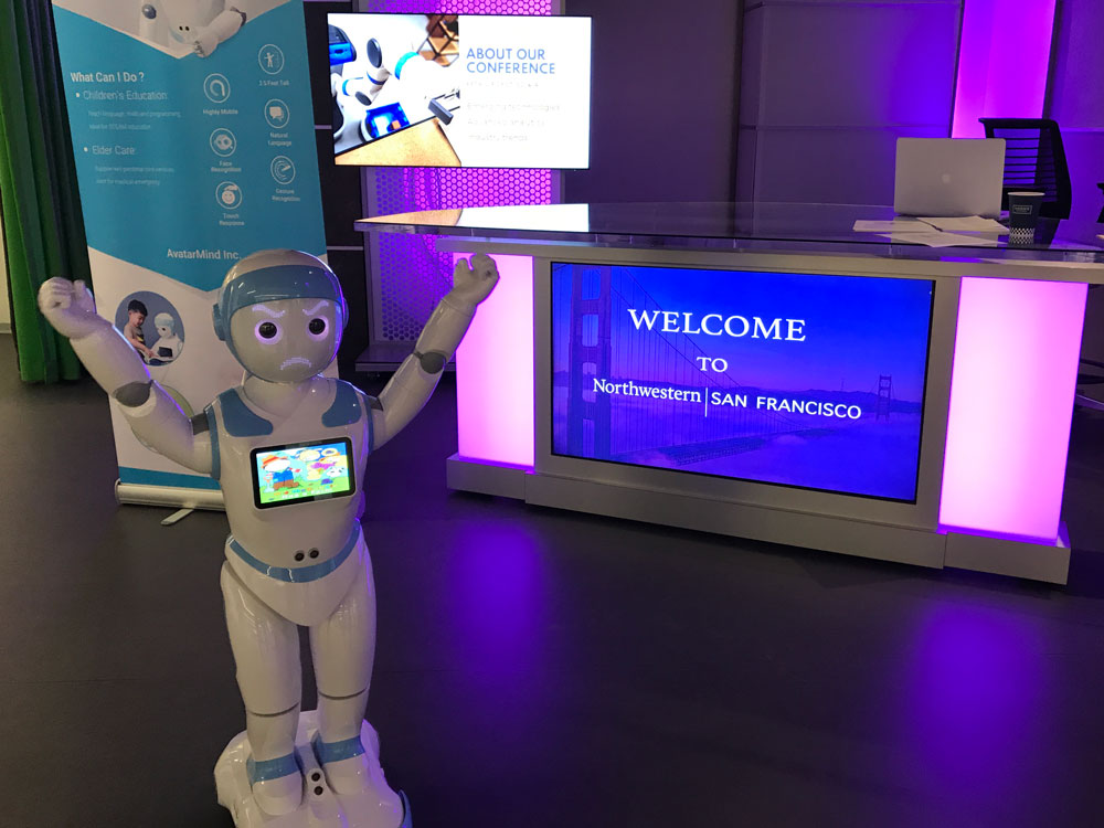 A robot stands in front of a sign that says Welcome to Northwestern San Francisco