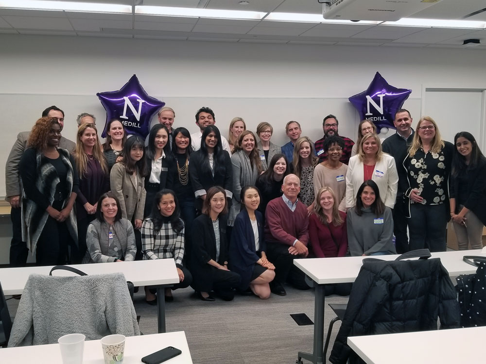 A large group of people pose for a photo in a classroom