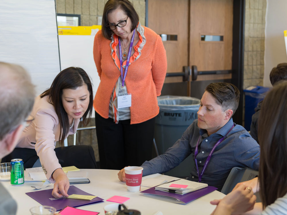 Local News Summit attendees talk around a table about ways to bolster local news