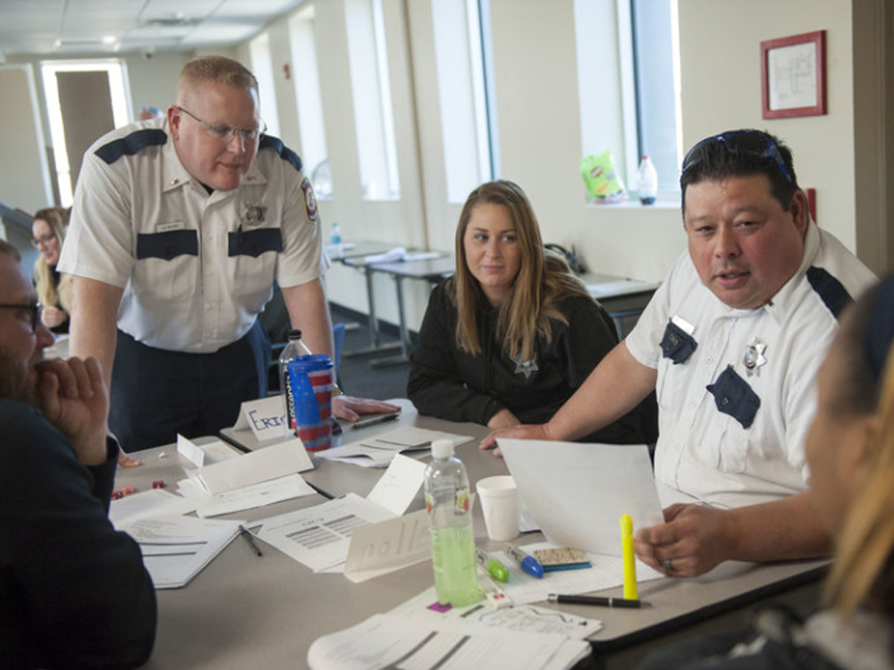 A man in a uniform talks with other people at a table