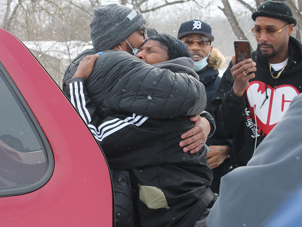 Standing in the snow next to a car and a crowd of onlookers, Kenneth Nixon hugs his mother.