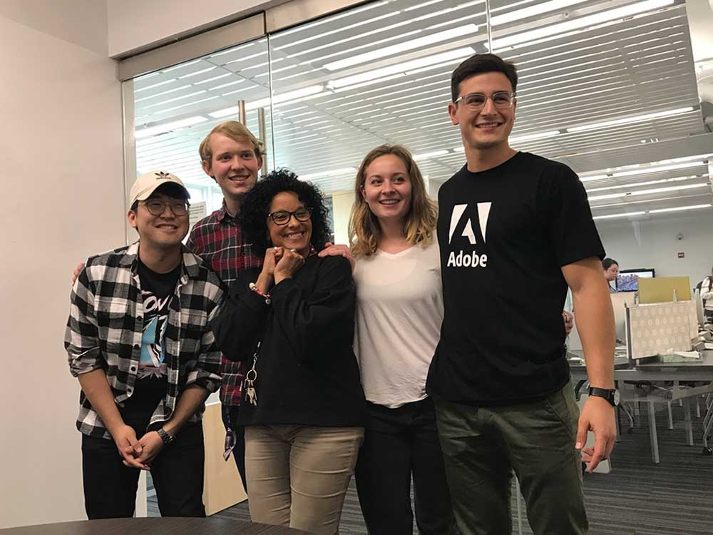 A professor poses for a photo with four students