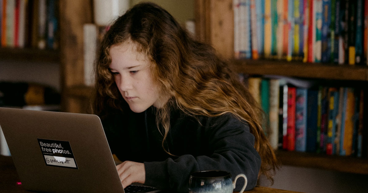 Teenager using a laptop at a library.