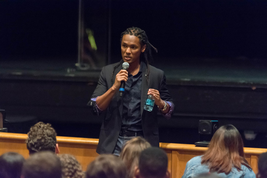 John Eligon holds a microphone and speaks to a crowd of students who stayed after the event to ask him questions