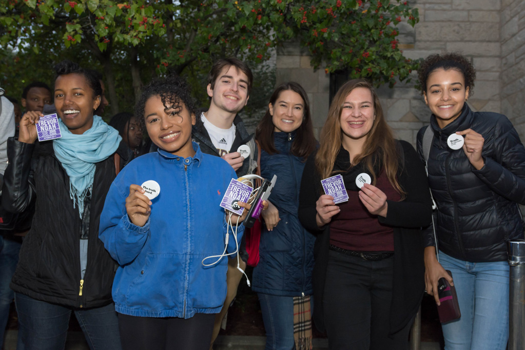 Students hold up giveaway items they received from Medill and The New York Times such as buttons and stickers
