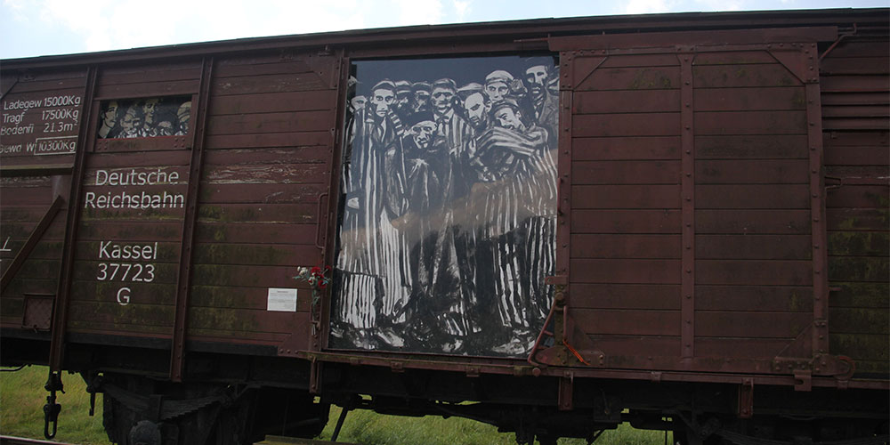 The open door of a train car depicting a large photograph of Holocaust prisoners in black and white.