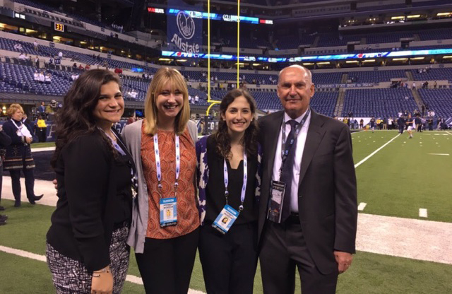 IMC Certificate students on the sidelines at a football stadium.