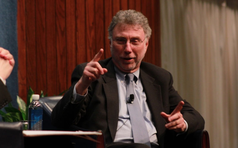 A man in a suit and tie speaking.