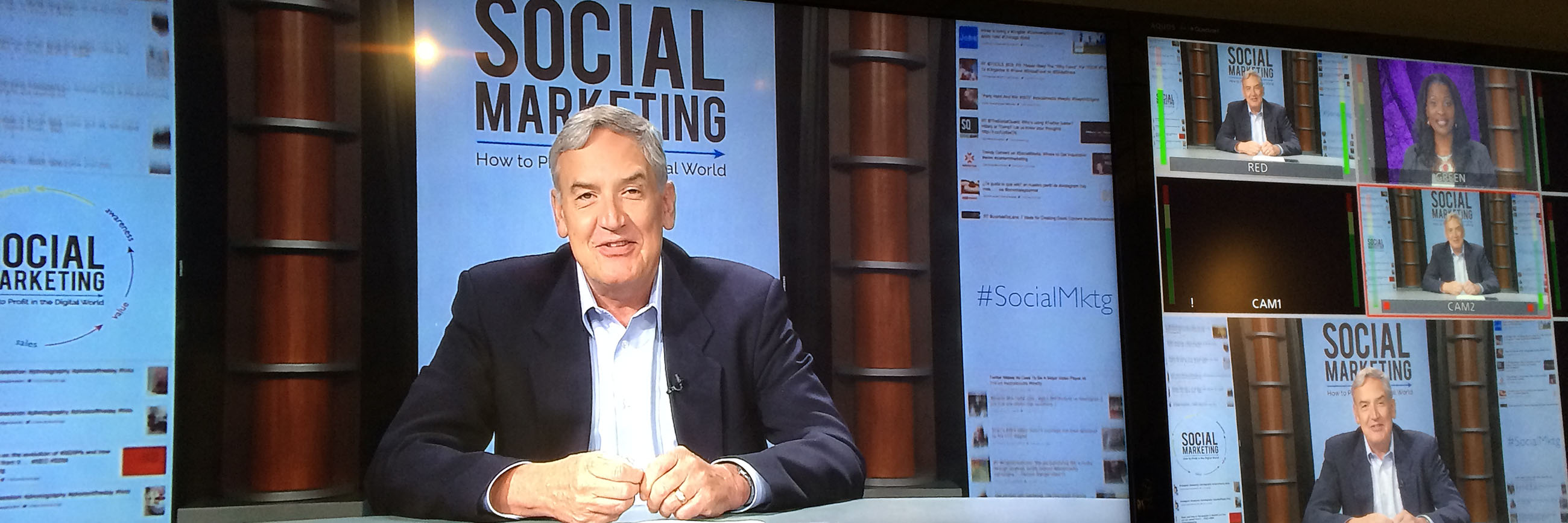 Presenter speaking at a desk with signs that say social marketing behind him